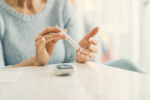 Women practicing self-care by testing her blood sugars at home